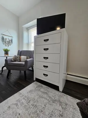 a white dresser in a living room with a chair at Rustic & Renovated 3 Bed - 8 Min Walk to Bridge St in Phoenixville