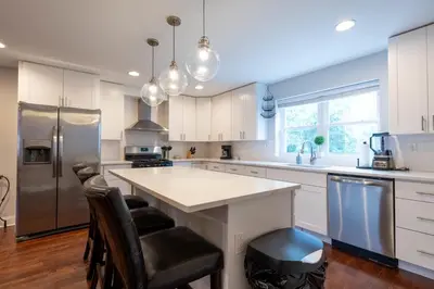 a kitchen with white cabinets and a large island at Stylish 3BR w Pool Table & Garage in Philadelphia