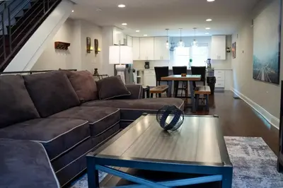 a living room with a brown couch and a table at Stylish 3BR w Pool Table & Garage in Philadelphia