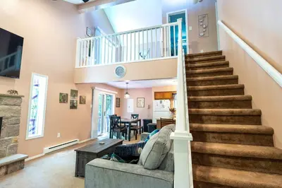a living room with stairs leading up to a dining room at Home Tucked into Towamensing Trails in Albrightsville