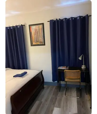 a bedroom with blue curtains and a desk and a bed at Cozy Room in Newark