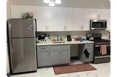 a kitchen with white cabinets and a stainless steel refrigerator at Cozy Room in Newark