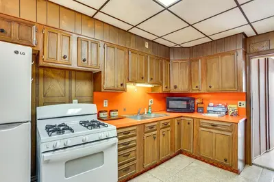 a kitchen with wooden cabinets and a white stove top oven at Playroom and Fenced Yard Mt Carmel Family Home! in Mount Carmel