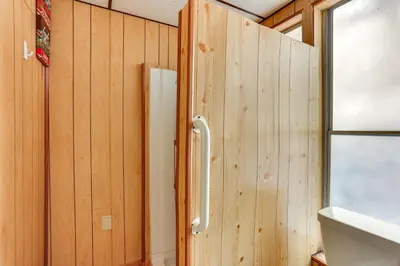 a bathroom with a wooden wall with a refrigerator at Playroom and Fenced Yard Mt Carmel Family Home! in Mount Carmel