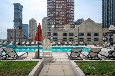 a pool with lounge chairs and a red umbrella at Global Luxury Suites Downtown Jersey City in Jersey City