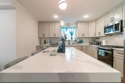 a kitchen with white cabinets and a large white counter top at Divine Essence in Newark