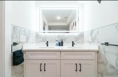 a white bathroom with a sink and a mirror at Divine Essence in Newark