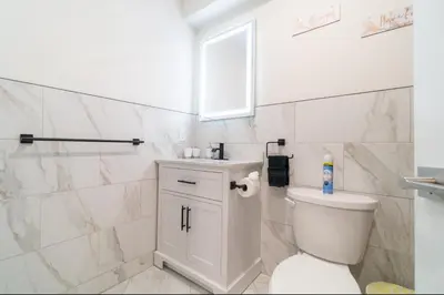a white bathroom with a toilet and a sink at Divine Essence in Newark