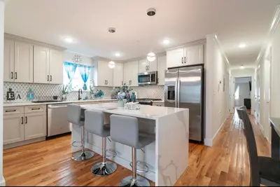 a kitchen with white cabinets and a kitchen island with bar stools at Divine Essence in Newark