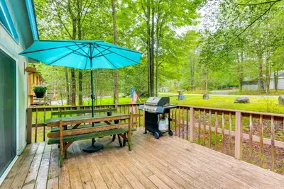 a picnic table with an umbrella and a grill on a deck at Deck and Fire Pit Pet-Friendly Pocono Lake Abode! in Pocono Lake