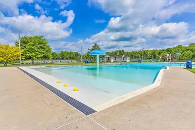 a large swimming pool with a blue umbrella at Deck and Fire Pit Pet-Friendly Pocono Lake Abode! in Pocono Lake