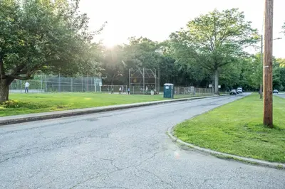 an empty street next to a park with trees at Luxury Apt in Passaic