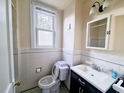 a bathroom with a toilet and a sink and a window at 3BR 1BA Near Train Station Monthly Deal in Elkins Park