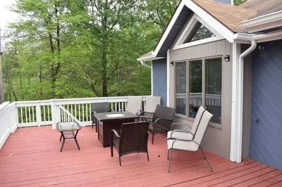 a deck with a table and chairs on a house at Big Blue Lake House complete with Game Room in Long Pond