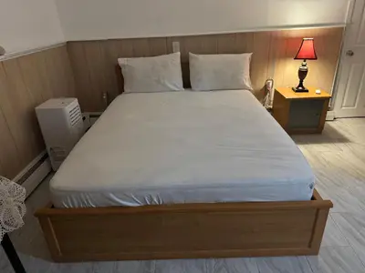 a large bed in a bedroom with a nightstand and a lamp at The White Pearl in Metuchen