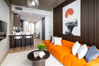 a living room with an orange couch and a kitchen at Luxury Full Floor Chelsea Apt St 7 in New York