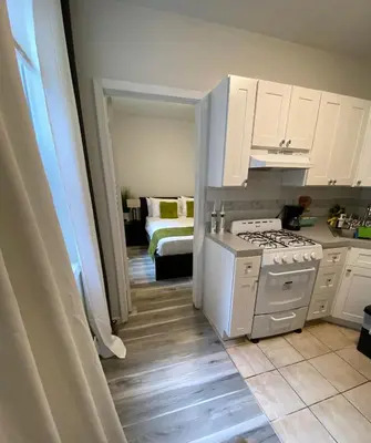 a kitchen with white cabinets and a stove top oven at Apart Studio West NY 12Mints From NYCity Times Square in West New York