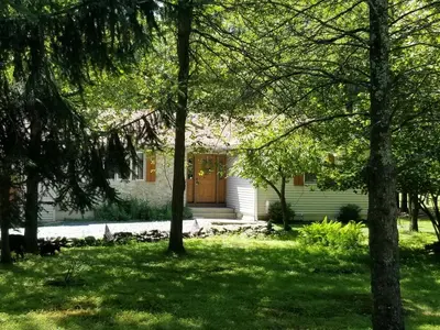 a white house with a brown door in a yard at Serenity and Fun all in one in this Cozy Pocono Cabin in Jim Thorpe