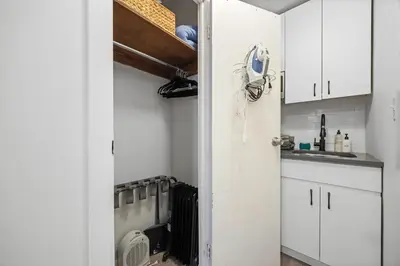 a kitchen with white cabinets and a door with a fan at Highly Recommended Studio Near Times Square in New York