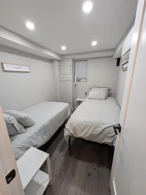 two beds in a small room with white walls at Extended Family Stay in Passaic