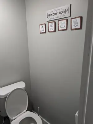 a bathroom with a white toilet and some pictures on the wall at Extended Family Stay in Passaic