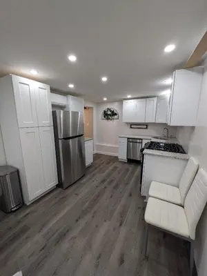 a kitchen with white cabinets and a white couch in it at Extended Family Stay in Passaic