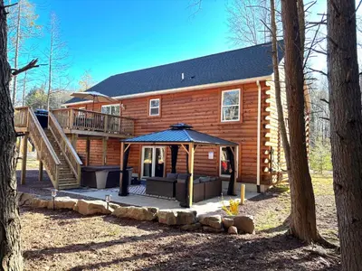 a log cabin with a porch and an umbrella at NEW Construction - 7 Bedroom Log Cabin in Blakeslee
