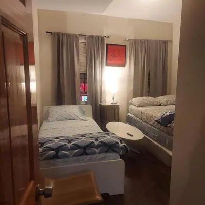 a small bedroom with two beds and a table at Double queen room 6 minutes walk to Penn station NYC EWR in Jersey City