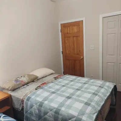 a small bedroom with a bed with a plaid blanket at Double queen room 6 minutes walk to Penn station NYC EWR in Jersey City