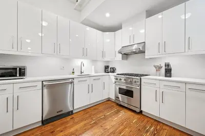 a white kitchen with white cabinets and a wooden floor at Massive SoHo Loft 4 Bedrooms 2 Bath 8 beds in New York