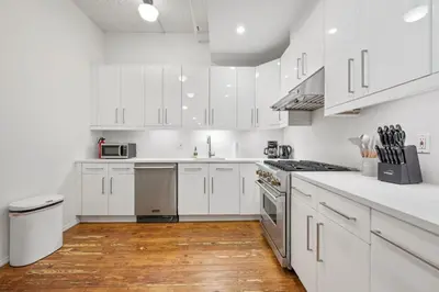 a white kitchen with white cabinets and wooden floors at Massive SoHo Loft 4 Bedrooms 2 Bath 8 beds in New York