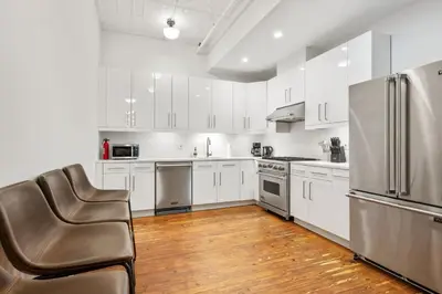 a kitchen with white cabinets and a stainless steel refrigerator at Massive SoHo Loft 4 Bedrooms 2 Bath 8 beds in New York