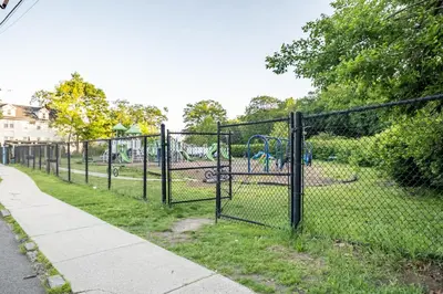 a chain link fence in a park with a playground at Jetted Tub Stay in Passaic
