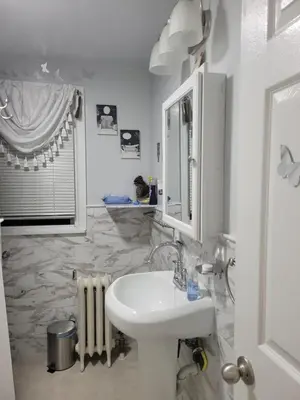 a white bathroom with a sink and a mirror at New bedroom in Roselle