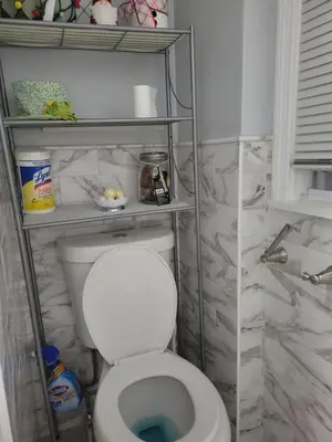 a bathroom with a white toilet with marble walls at New bedroom in Roselle