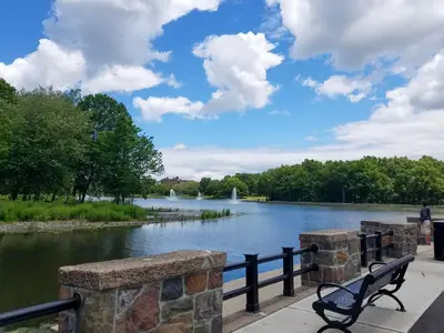 a park bench next to a lake with a fountain at NYC Loft Studio Near MetLife World Cup Stadium & Times Square in North Bergen