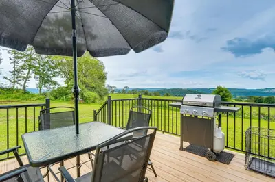 a grill and a table with an umbrella on a deck at Comfortable Muncy Home with Serene Views! in Muncy