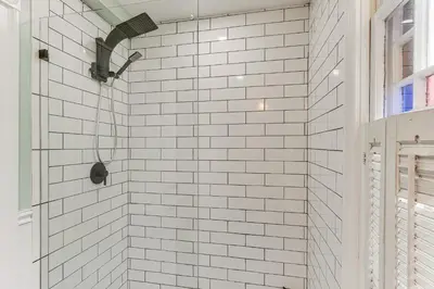 a white tiled shower with a black shower head at Walk to Hudson River Pet-Friendly Home with Views! in Newburgh