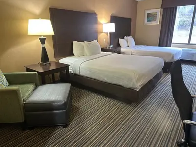 a hotel room with two beds and a chair at Wingate by Wyndham Harrisburg Near Hershey in Harrisburg