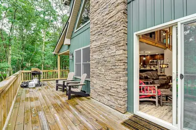 a deck with a stone wall and a house at Forest Views and Hot Tub Poconos Cozy Cabin in Albrightsville
