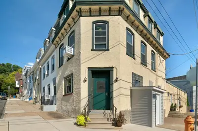 a brick building with a green door on a street at Large Bi-level Apartment in Heart of Manayunk in Bala-Cynwyd