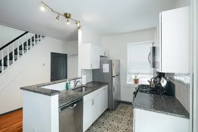 a white kitchen with a sink and a refrigerator at Large Bi-level Apartment in Heart of Manayunk in Bala-Cynwyd
