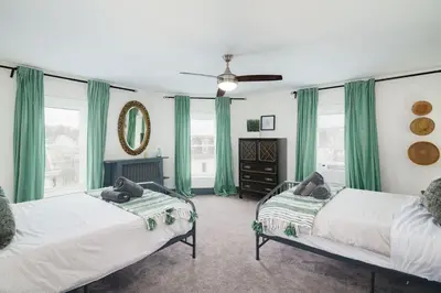 two beds in a room with green curtains at Large Bi-level Apartment in Heart of Manayunk in Bala-Cynwyd