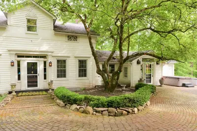 a white house with a tree and a brick driveway at Ulster County Farmhouse Near Waterfalls and Winery! in Pine Bush
