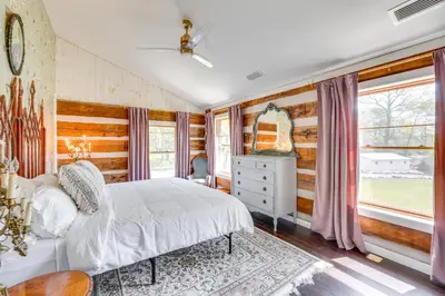 a bedroom with a white bed and wooden walls at Grill and Fire Pit Eclectic Ulster County Cabin in Pine Bush