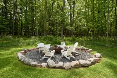 a circular fire pit in the middle of a yard at Grill and Fire Pit Eclectic Ulster County Cabin in Pine Bush