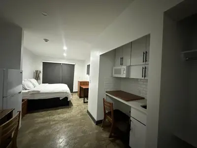 a bedroom with a bed and a kitchen with a desk at Tribeca Hotel FiDi in New York