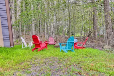 a group of colorful chairs sitting in the grass at Wooded Tobyhanna Home with Fire Pit and Lake Access! in Tobyhanna