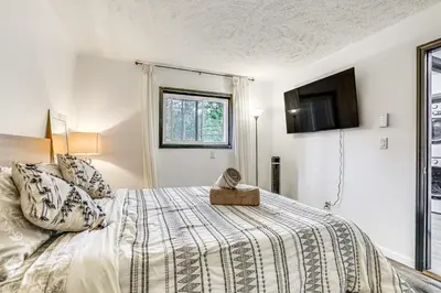 a bedroom with a bed and a tv on the wall at Wooded Tobyhanna Home with Fire Pit and Lake Access! in Tobyhanna