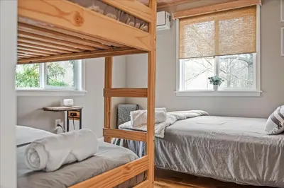 two bunk beds in a room with two windows at Pocono Scandinavian Cottage cottage in Tobyhanna